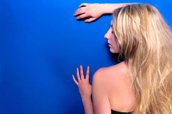 Mavi duvar karşı sarışın kız — Stok fotoğraf