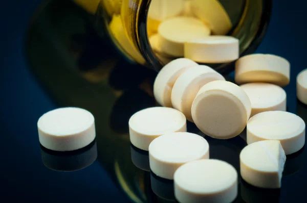 Pillole mediche dalla loro bottiglia su sfondo nero — Foto Stock
