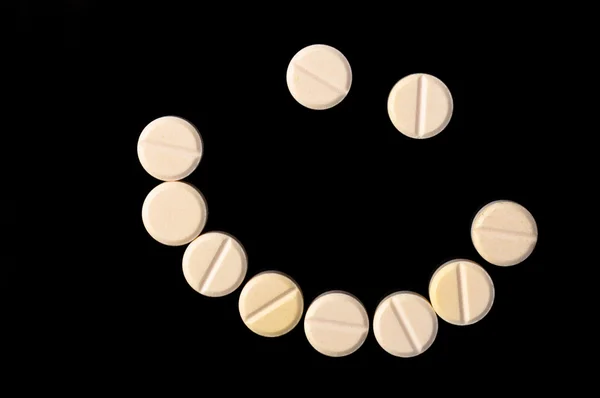 Smiling face made out of pills on black background — Stock Photo, Image