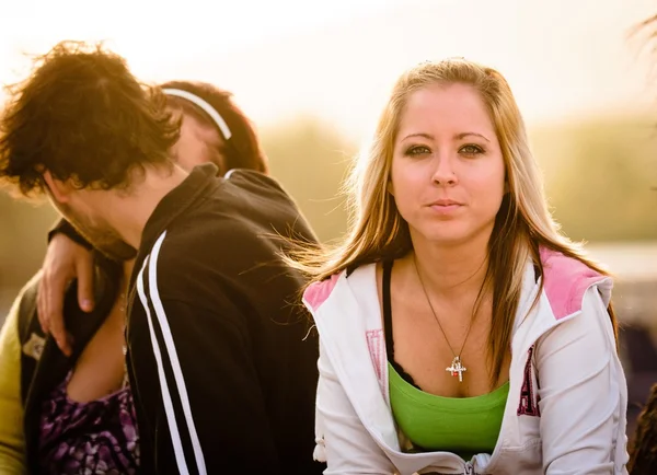 Proud girl with Young couple kissing in the background — Stock Photo, Image