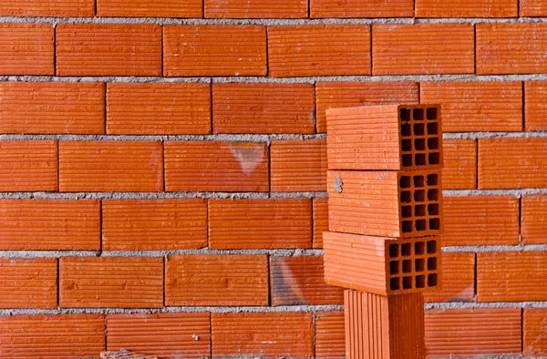 Mur z cegły ze stosem nowych cegieł — Zdjęcie stockowe