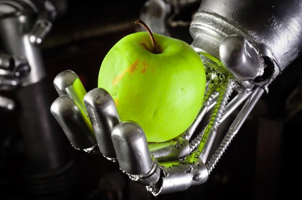 Рука робота держит свежее яблоко — стоковое фото