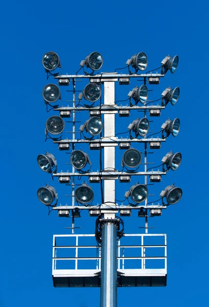 Iluminación del estadio con muchos reflectores contra el cielo azul —  Fotos de Stock