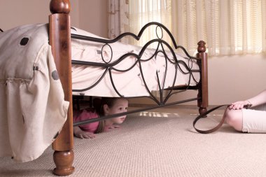 The child hides under a bed. Violence in a family. clipart