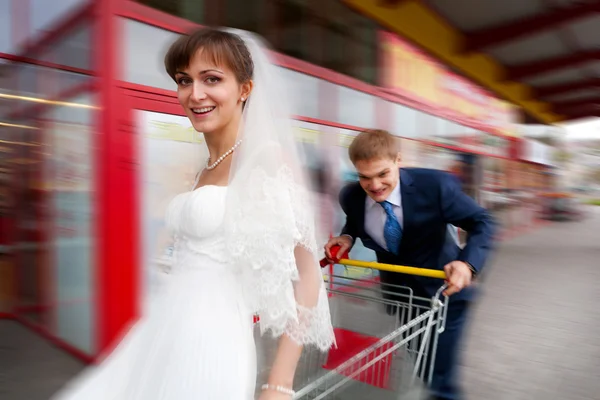 Noiva e noivo montando no carrinho de compras — Fotografia de Stock