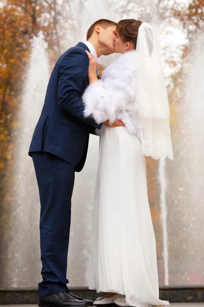 Bride and groom kissing against fountain — Stock Photo, Image