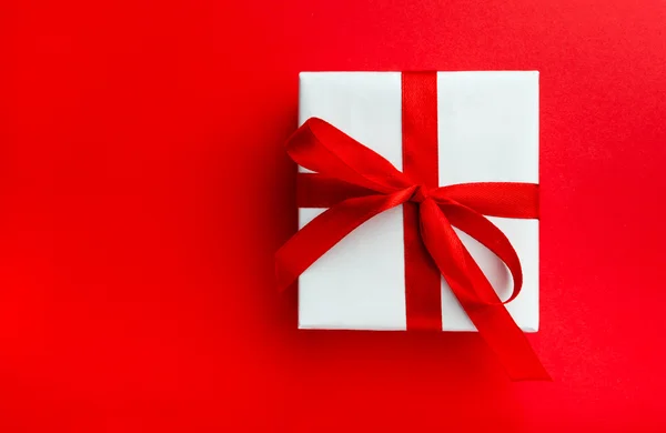 Klein cadeautje met rode strik op rode achtergrond. — Stockfoto