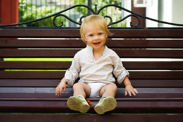 Cute little baby sitting on bench — Zdjęcie stockowe