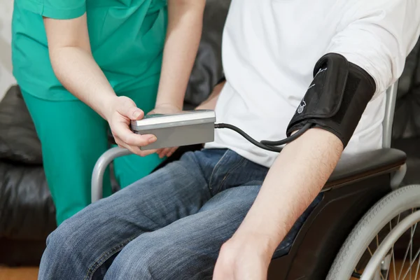 Blood pressure check for young adult in wheelchair. — Stock Photo, Image