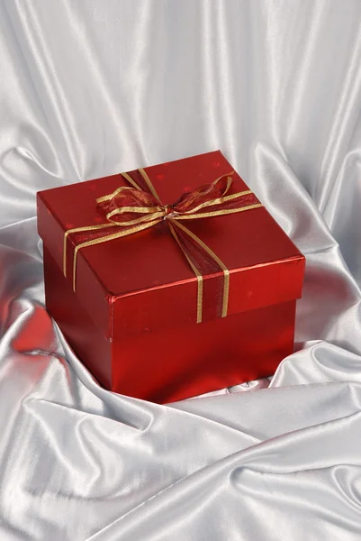 Red gift box on white satin — Stock Photo, Image