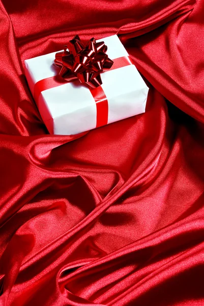 Gift box on red satin background — Stock Photo, Image