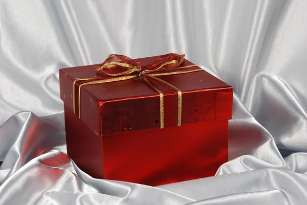 Rode geschenkdoos op witte satijnen achtergrond — Stockfoto