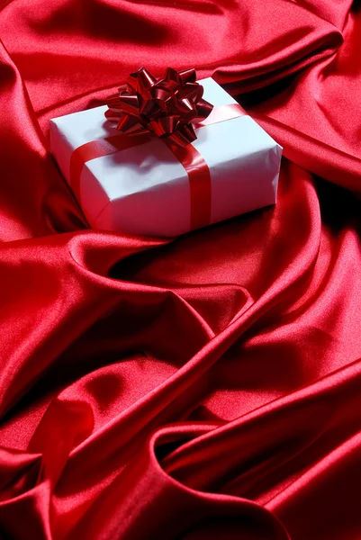 Gift box on red satin background — Stock Photo, Image