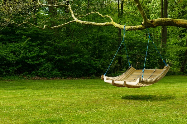 Swing bench in lush garden — Stock Photo, Image