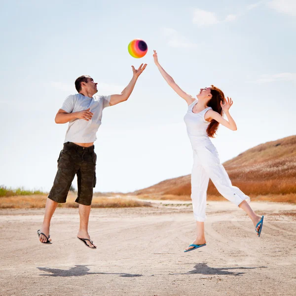 Couple jumping to catch a ball — Stock Photo, Image