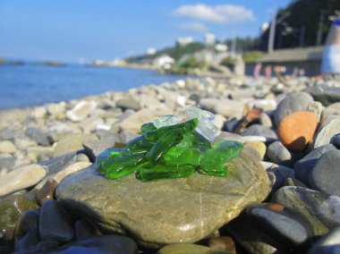 Green and white broken glass on the summer beach clipart