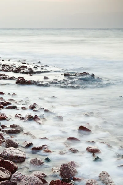 Valoun kamenné pláž čtení moře na západ slunce — Stock fotografie