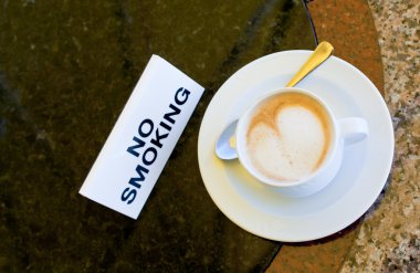 Cup of cappuccino on no-smoking table clipart