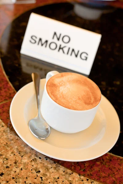 Cup of cappuccino on no-smoking table — Stock Photo, Image