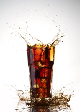 Ice cube droped in cola glass and cola splashing clipart