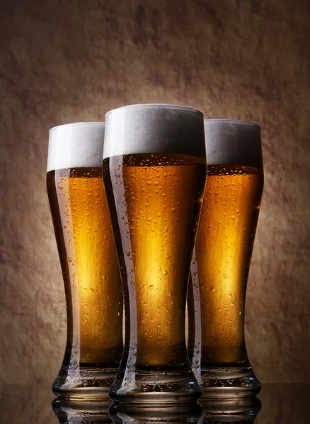 Three cold Beer into glass on a old stone — Stock Photo, Image