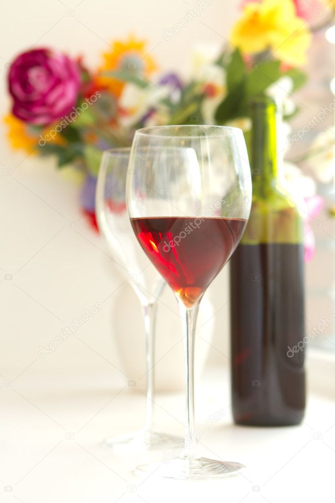 Wine glasses filled with red wine and wine bottle