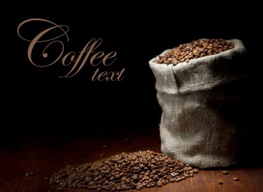 Burlap sack of coffee beans against dark wood background clipart