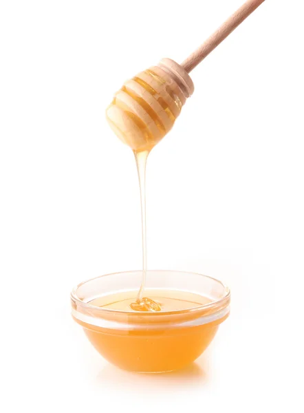 Honey pouring from drizzler into the bowl. Bowl is on a white — Stock Photo, Image