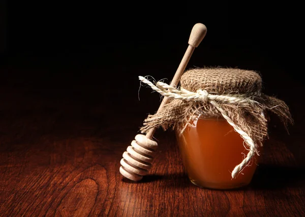 Pot of honey and wooden stick are on a table. — Stock Photo, Image