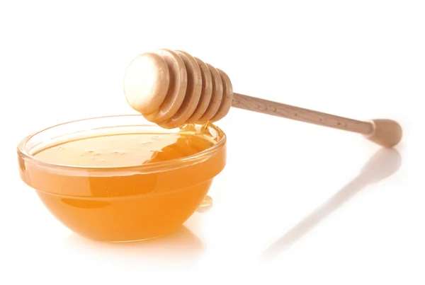 Honung hälla från drizzler i skålen. skålen är på en vit — Stockfoto
