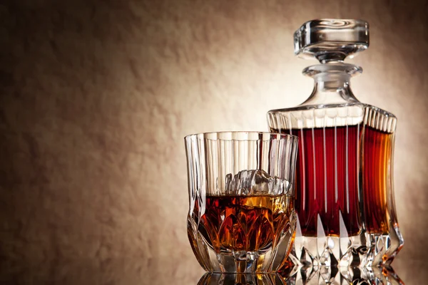 Glass and decanter of brandy on a old stone background — Stock Photo, Image