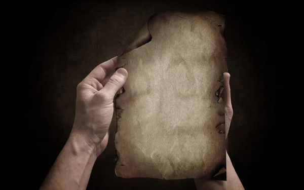 Hands bring the old paper on the dark background — Stock Photo, Image