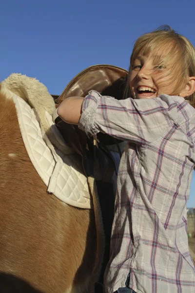 Mädchen glücklich Sättel auf Pony — Stockfoto