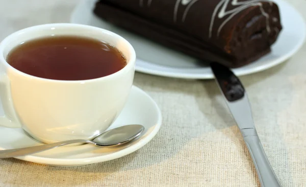 stock image Cup tea with a roll, a spoon and a knife