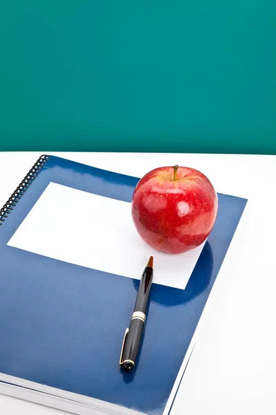 Красное яблоко и учебник — стоковое фото