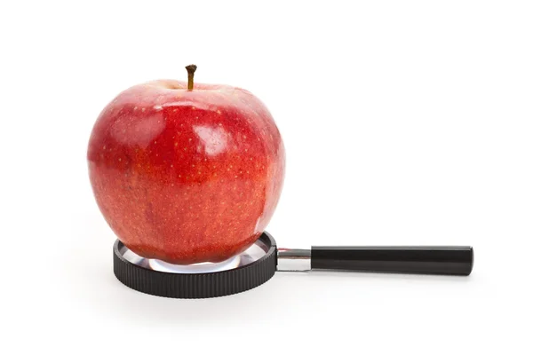 Красное яблоко и лупа — стоковое фото