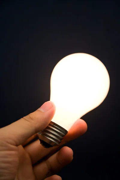Mão segurando uma lâmpada brilhante — Fotografia de Stock