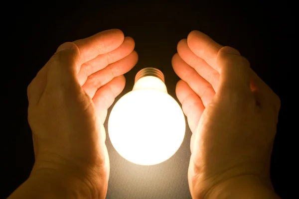 Hand und eine helle Glühbirne — Stockfoto