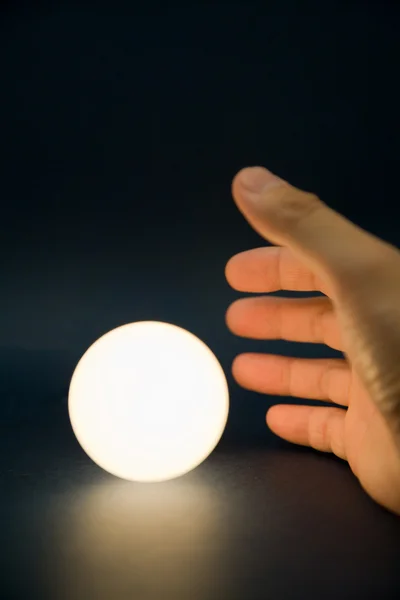 Mão tocando uma bola brilhante — Fotografia de Stock