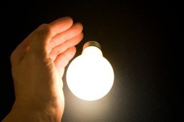 Hand and a Bright Light Bulb clipart