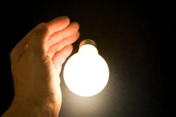 Hand and a Bright Light Bulb Royalty Free Stock Photos