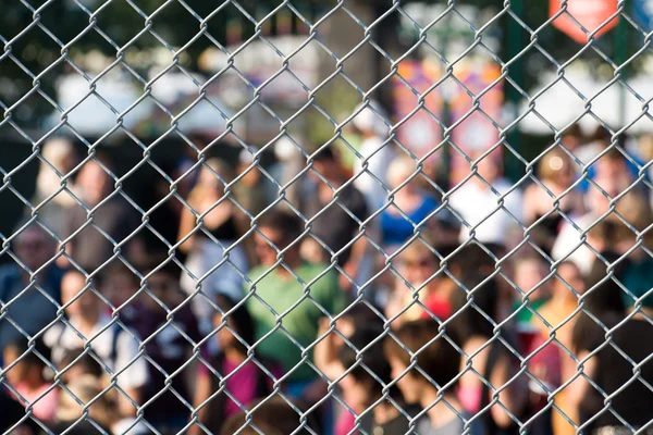 Metal netting and crowd — Stock Photo, Image
