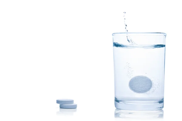 Kolsyrad piller splash i ett glas vatten. — Stockfoto