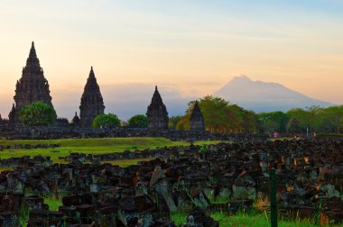 Prambanan hindu temple in Yogyakarta with Merapi volcano on the background clipart