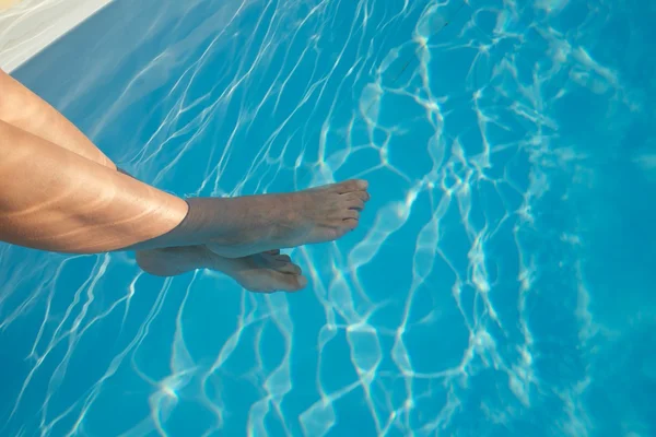 Benen gekruist in blauwe zwembad — Stockfoto