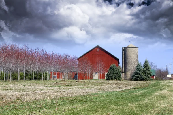 Красная ферма с бурным небом — стоковое фото