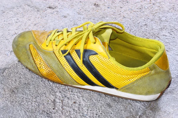 Старая желтая обувь на бетоне — стоковое фото
