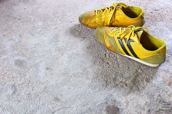 Old yellow shoes on concrete — Stock Photo, Image