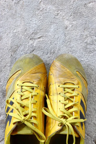 Old yellow shoes on concrete — Stock Photo, Image