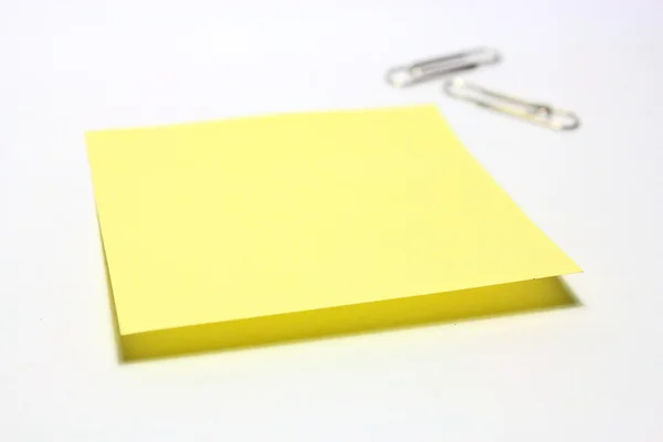 Жовта нота з затискачем на білому тлі — стокове фото